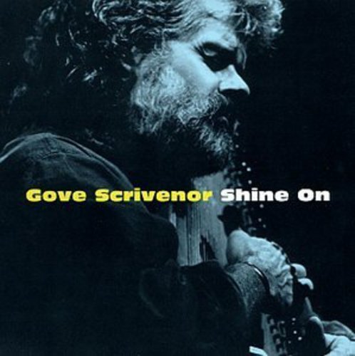 Album cover featuring a man with a beard playing a guitar, dark background.