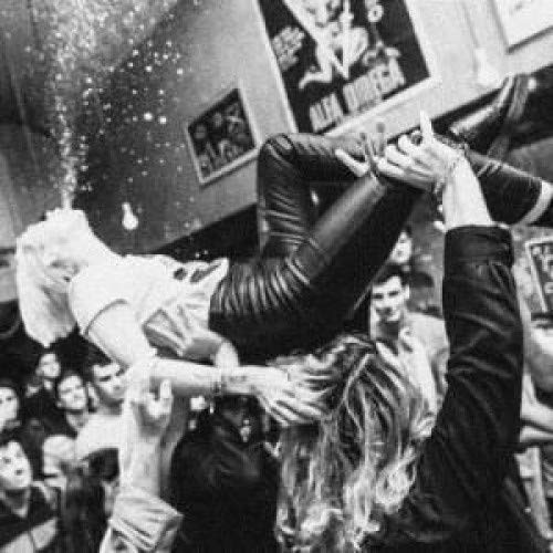 Black and white photo of people stage diving at a concert.