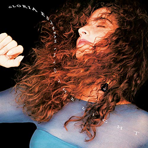Gloria Estefan's album cover featuring a woman with long, flowing hair against a black background.