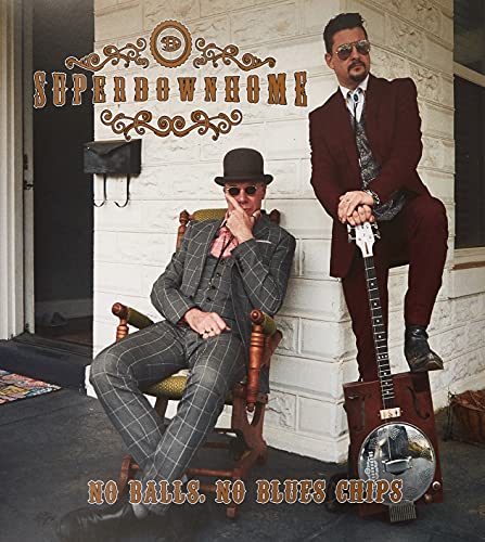 Two men in suits pose with a banjo on a porch.