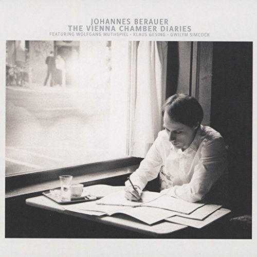 "Black and white album cover with a man writing at a desk by a window."