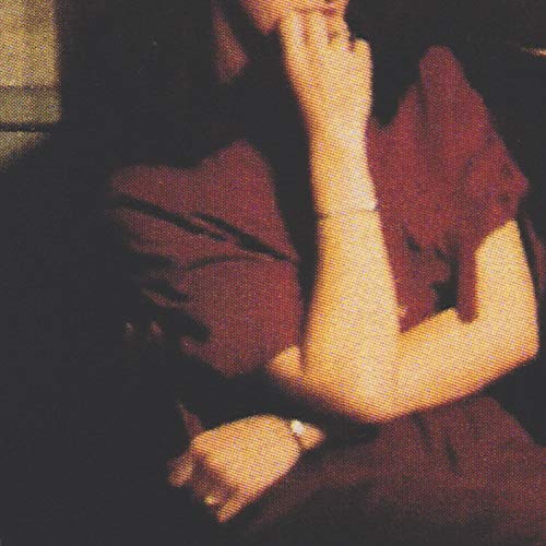 Close-up of a person with eyes closed, arms crossed, grainy texture.