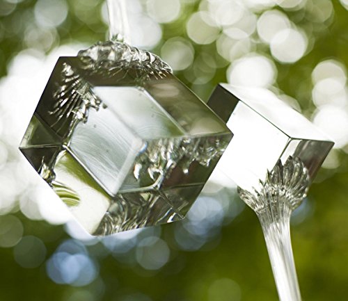 A crystal ornament hangs from a string, reflecting light against a bokeh green background.