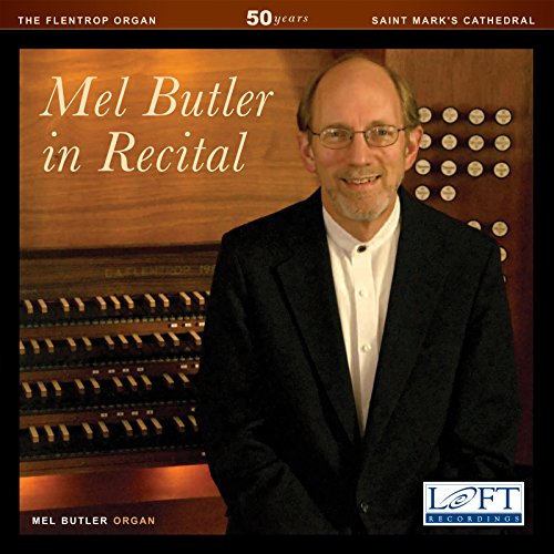 Mel Butler, organist, smiles beside a pipe organ in a cathedral.