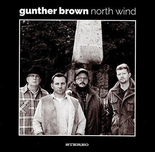 "Black and white album cover with four men standing by a monument."