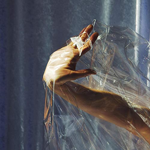 A hand holds crumpled plastic wrap against a dark, textured background.
