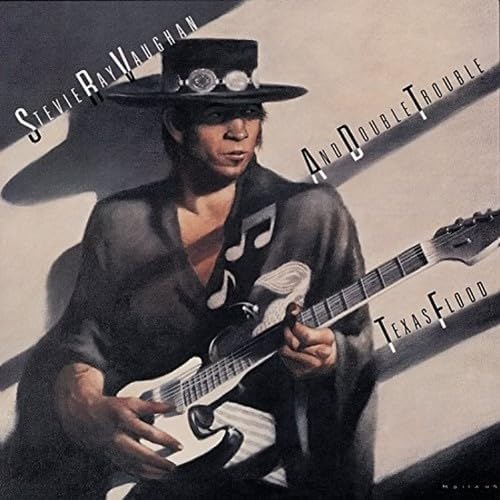 Stevie Ray Vaughan wearing a wide-brimmed hat while playing an electric guitar.