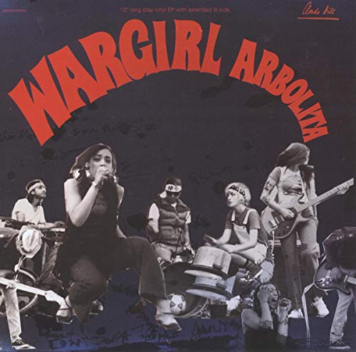 The image shows a vinyl record cover with a band performing on stage. alt text: "Wargirl Arbolita vinyl record cover featuring a band performing in black and white."
