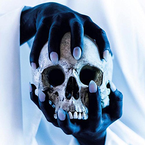 Gloved hands holding a human skull with white-painted fingernails against a white background.