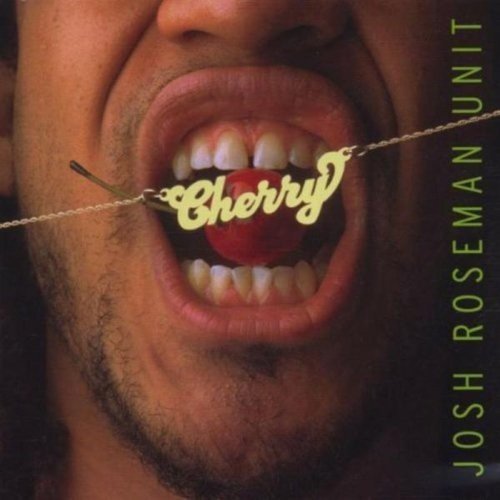 A man's mouth holding a cherry on a stick with "Cherry" written on it.