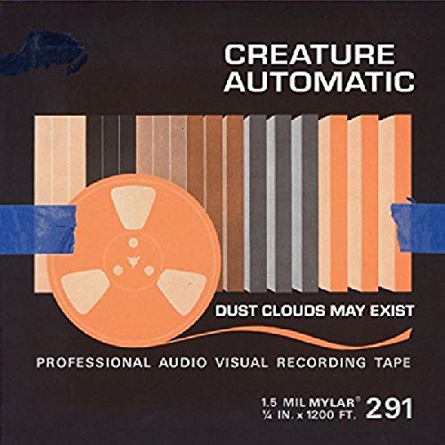 The image shows a reel of tape with the words "CREATURE AUTOMATIC" and "DUST CLOUDS MAY EXIST". For accessibility purposes, a suitable alt text could be: "Reel of orange tape on a black background."