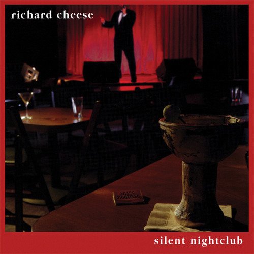 Album cover: man on stage, empty tables, and a bidet in the foreground.