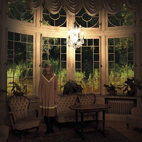 Woman in a room with large windows and ornate furniture.