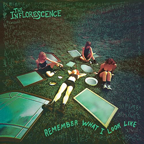 CD cover: three people lying on grass surrounded by chalkboards.