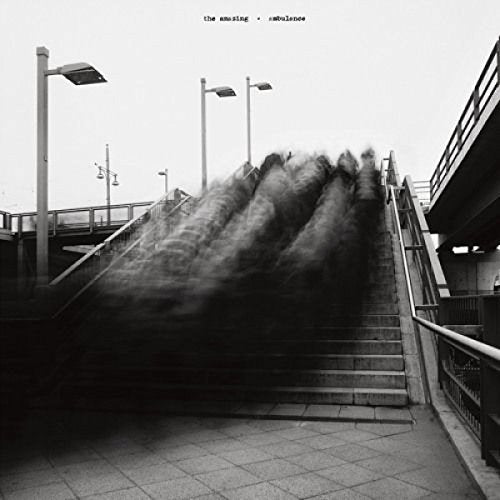 Black and white album cover with blurred figures on stairs under a bridge.