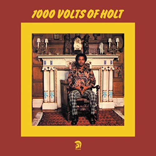 "Album cover with man sitting in chair, surrounded by ornate fireplace on red background."