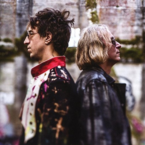 "Album cover with two men standing back-to-back, wearing dark jackets, against a brick wall."