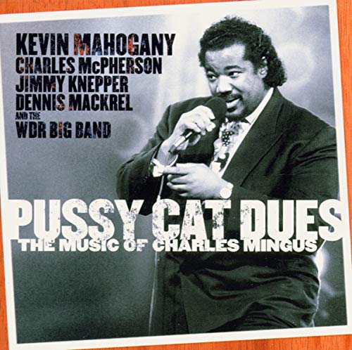 Album cover featuring a man holding a microphone, with orange background and white text.