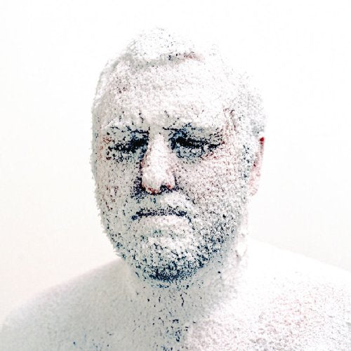 A man covered in white powder, looking directly at the camera, against a white background.