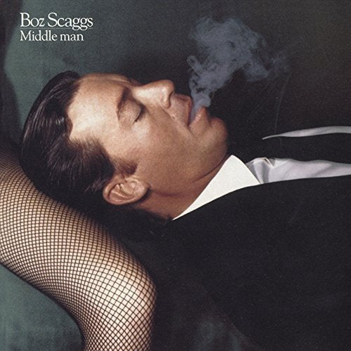"Album cover with man reclining, smoking, and a woman's stocking-clad arm."