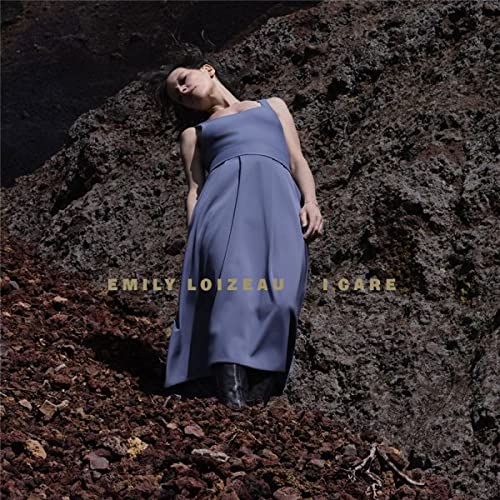 Woman in blue dress reclines on rocky, textured ground.
