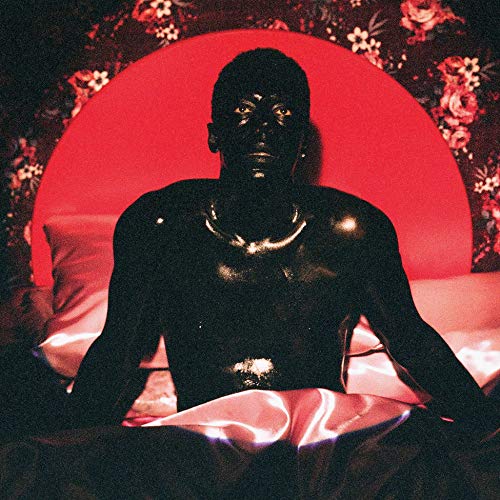 "Man sitting on a bed with a red circle behind him."
