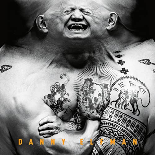 Black and white portrait of Danny Elfman with intricate tattoos on his chest.
