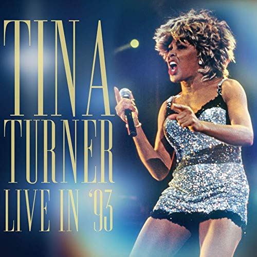 Tina Turner singing into a microphone on a concert stage.