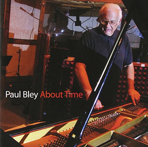 "Album cover with older man standing beside an open grand piano, dimly lit studio background."