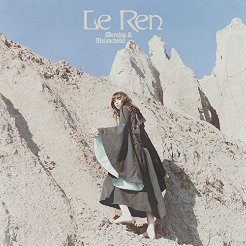 Album cover: woman in black robe stands before desert mountains.