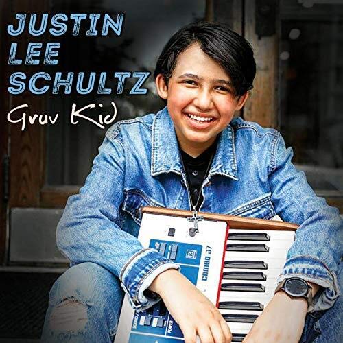 "Album cover featuring a smiling boy holding a keyboard, wearing a denim jacket."