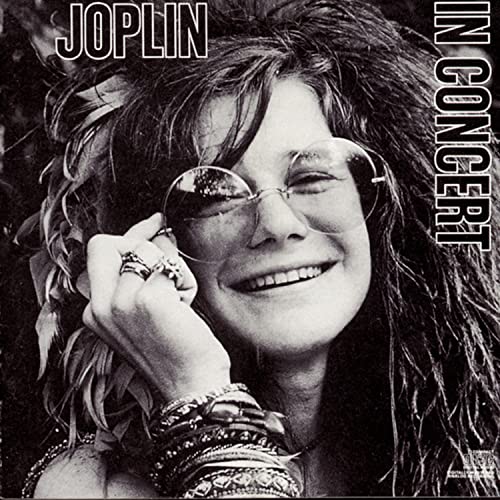 Black and white portrait of Janis Joplin with sunglasses and jewelry.
