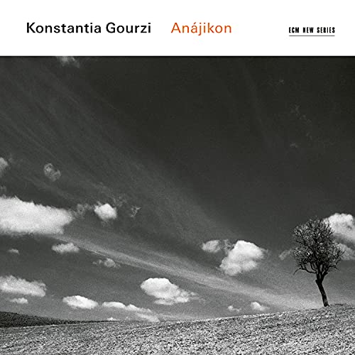 "Album cover with black and white landscape photo, lone tree, and cloudy sky."