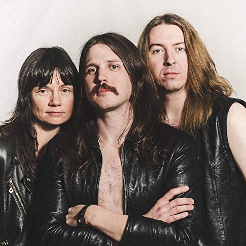 Three musicians with long hair pose in leather jackets.