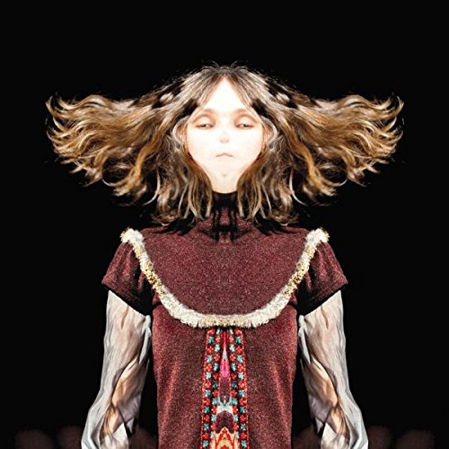 The image depicts a woman with flowing hair wearing a maroon top with white trim.