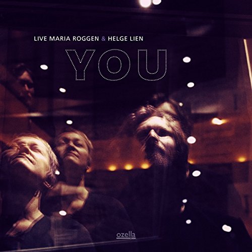 "CD cover with three musicians and 'YOU' in dotted letters, dark background, lit stage."