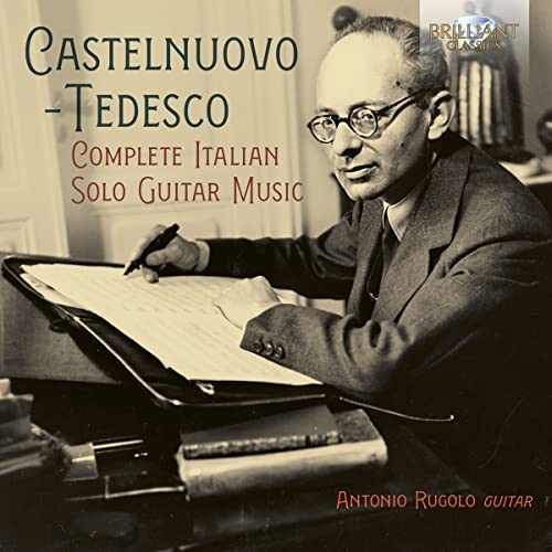 Sepia-toned portrait of a man composing with a guitar and sheet music.