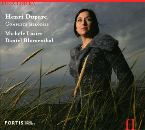 Woman in gray coat stands among tall grass, cloudy sky behind her, on CD cover.