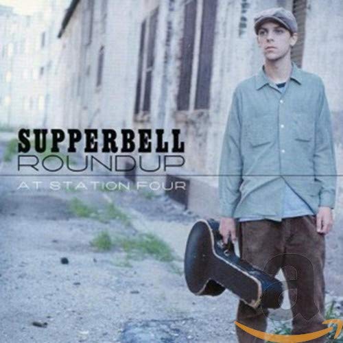 CD cover: man with cap and boot in front of building.