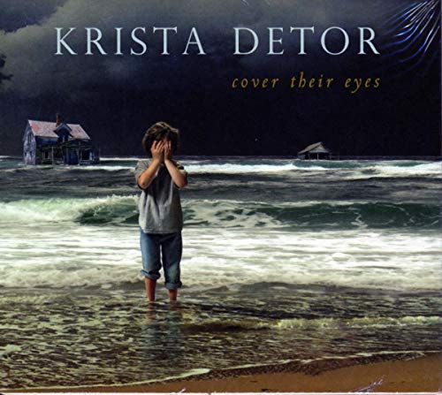 Boy covering eyes stands in water before dilapidated houses.