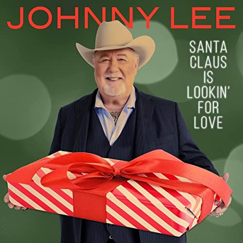 Johnny Lee in a cowboy hat holds a large striped gift.