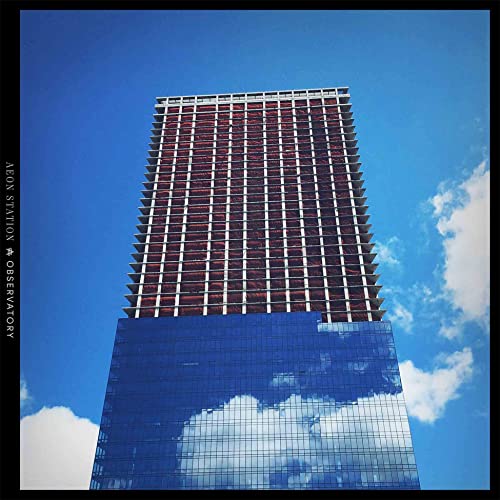 Tall, modern building with reflective glass against a bright blue sky.