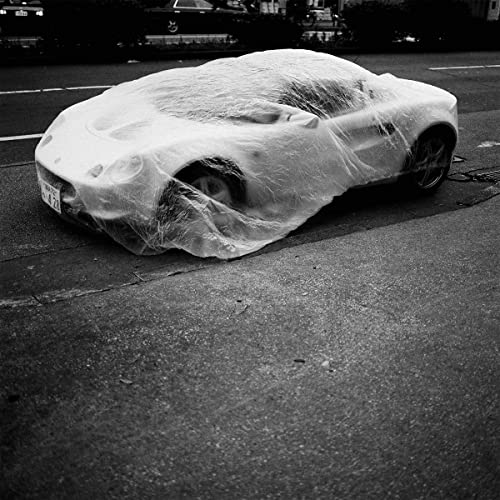 Black and white photo of a car covered with plastic wrap.