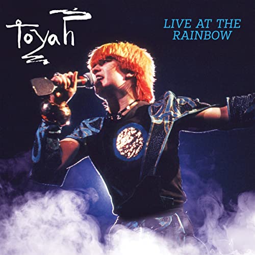 Toyah Wilcox singing into a microphone on a smoky stage.