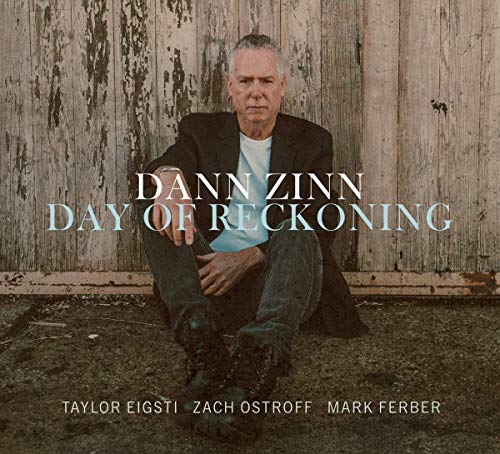 "Album cover featuring a man sitting against a worn wooden wall."