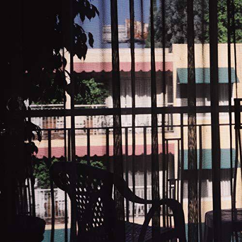 View through a screen of a building and patio furniture.