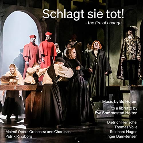 Opera stage scene with figures in dark robes and red garments.