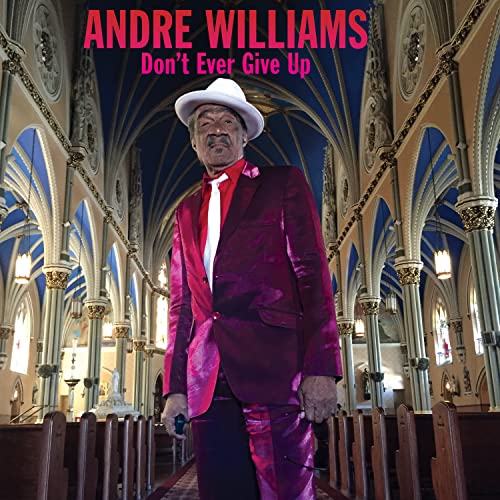 Andre Williams in a red suit and white hat, standing in a church.