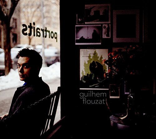 Man looking away, storefront window with portraits and winter foliage.