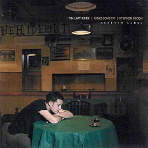 "Album cover: man resting head on table in a dimly lit restaurant."
